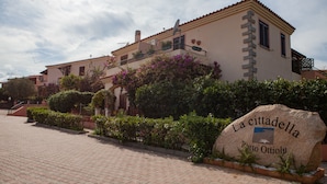 A stone sign with "La cittadella Porto Ottavio" inscribed, a building with balconies, and a paved walkway. - FANTASTICO PORTO OTTIOLU GR4 (Budoni)