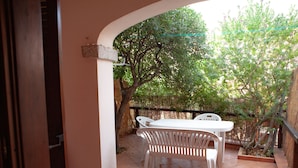 An outdoor patio with a white table and chairs, surrounded by a wooden fence and trees. - FANTASTICO PORTO OTTIOLU GR4 (Budoni)