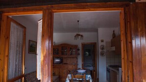 A wooden-framed doorway leading into a living room with a patterned table and chairs, a television, and a cabinet with glass doors. - FANTASTICO SAN TEODORO FS-AH01 (San Teodoro)