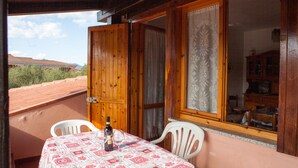 A balcony with a table set for two, a bottle of wine, and a view of the surrounding area. - FANTASTICO SAN TEODORO FS-AH01 (San Teodoro)