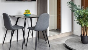 A modern dining area with a table and two chairs, a potted plant, and a television mounted on the wall. - Edgware Road Apartments (London)