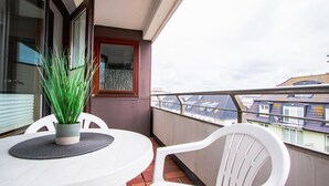 A balcony with a table and chairs, a potted plant, and a view of buildings. - App. Bagehorn 10 (Westerland)