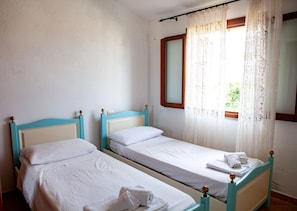 A room with two single beds, a window with lace curtains, and a wooden headboard. - FANTASTICO PEDRAMI 1 (Budoni)