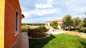 A courtyard with a tiled floor, a stone wall, and a small garden area with orange flowers. - FANTASTICO PEDRAMI 1 (Budoni)