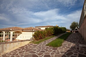 A pathway leading to a building with a tiled roof and a stone-paved walkway. - FANTASTICO PEDRAMI 1 (Budoni)