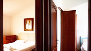 A bedroom with a bed, wooden wardrobe, and a window with blinds. - FANTASTICO PEDRAMI 1 (Budoni)
