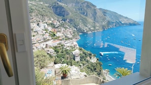 Une ville côtière avec des bâtiments construits sur une colline, une mer bleue et limpide, et des bateaux.