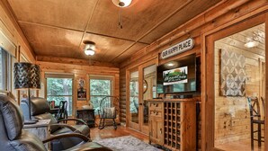 A cozy cabin interior with leather recliners, a television, and a 'Our Happy Place' sign. - ​​​​​​​Jagged Owl by Mountain Oasis | Dog-Friendly Cabin in Coosawattee River Resort (Ellijay)