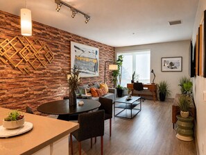 Een moderne woonkamer met een houten accentmuur, een eetgedeelte met een ronde tafel en een zithoek.