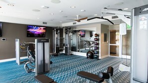 A gym with exercise equipment, a television, and a patterned floor. - Resort-Style Condo 3 Miles to Disney (Fullerton)