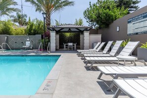 Un espace piscine avec des chaises longues et un coin salon abrité.