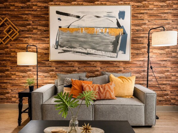 A modern living room with a grey sofa, a coffee table, and a painting on the wall.