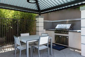 An outdoor patio with a grill, table, and chairs. - Resort-Style Condo 3 Miles to Disney (Fullerton)