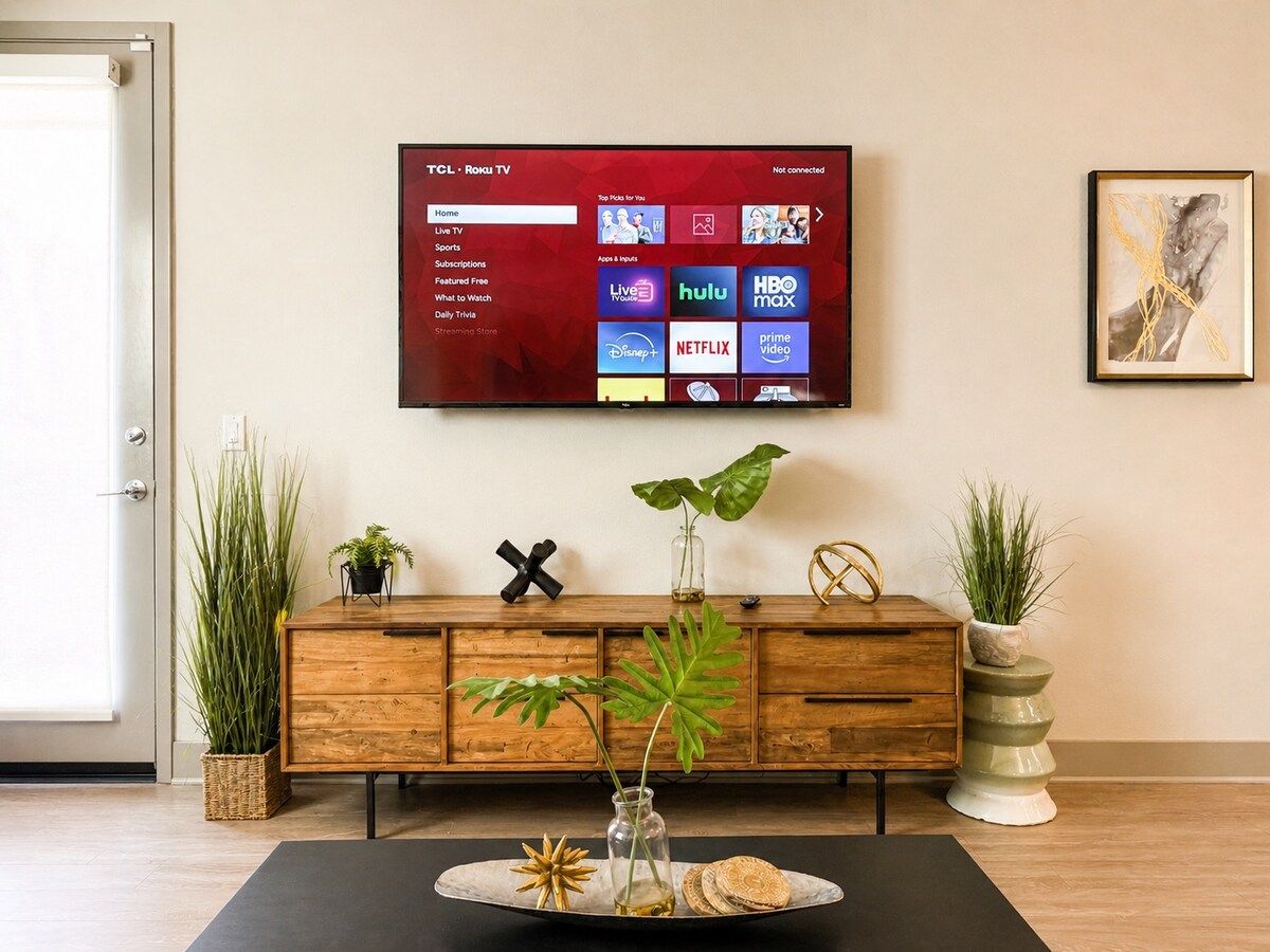 Living room with a smart TV and stylish media console framed by greenery