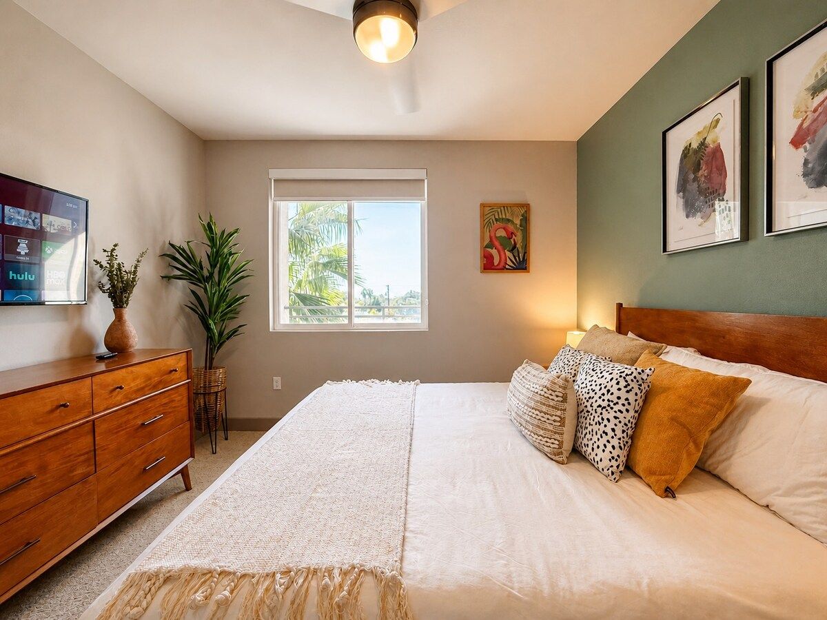 Bright bedroom with a smart TV, dresser and sunny window