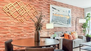 A modern living room with a wooden wall, a round table, and a sofa. - Resort-Style Condo 3 Miles to Disney (Fullerton)