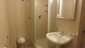 A bathroom with a glass-enclosed shower, a white sink, and a small toilet. - Ostello Il Volto (Potenza)