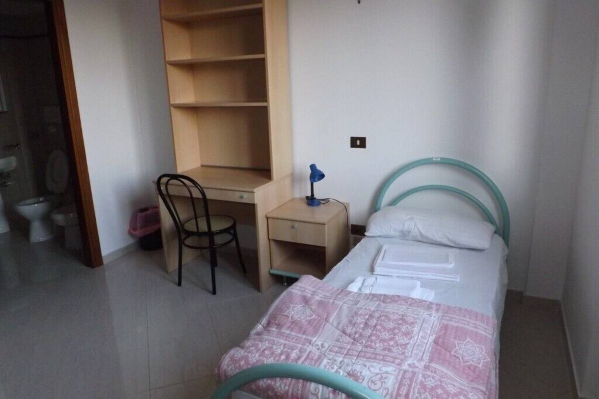 A small, clean room with a bed, a desk, and a chair.