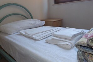 A single bed with a metal headboard, a wooden nightstand, and a window with blinds. - Ostello Il Volto (Potenza)