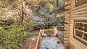 Un jacuzzi en una terraza de madera con vistas a un paisaje boscoso.