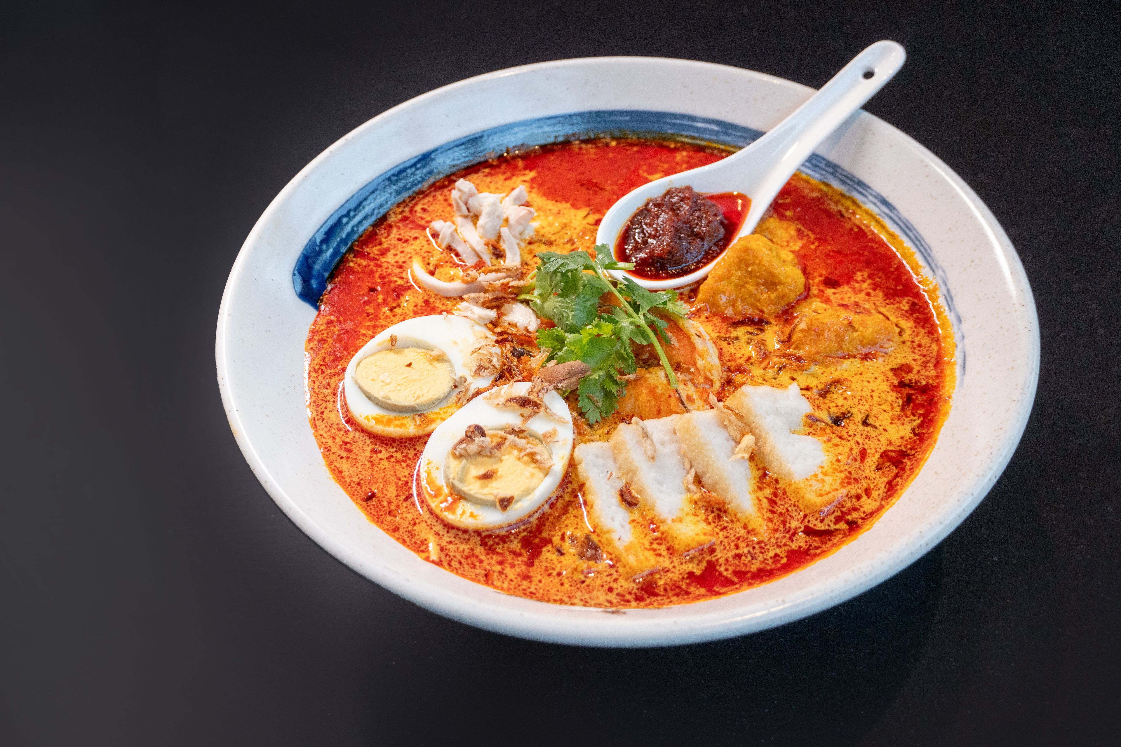 A bowl of soup with various ingredients and a spoon.