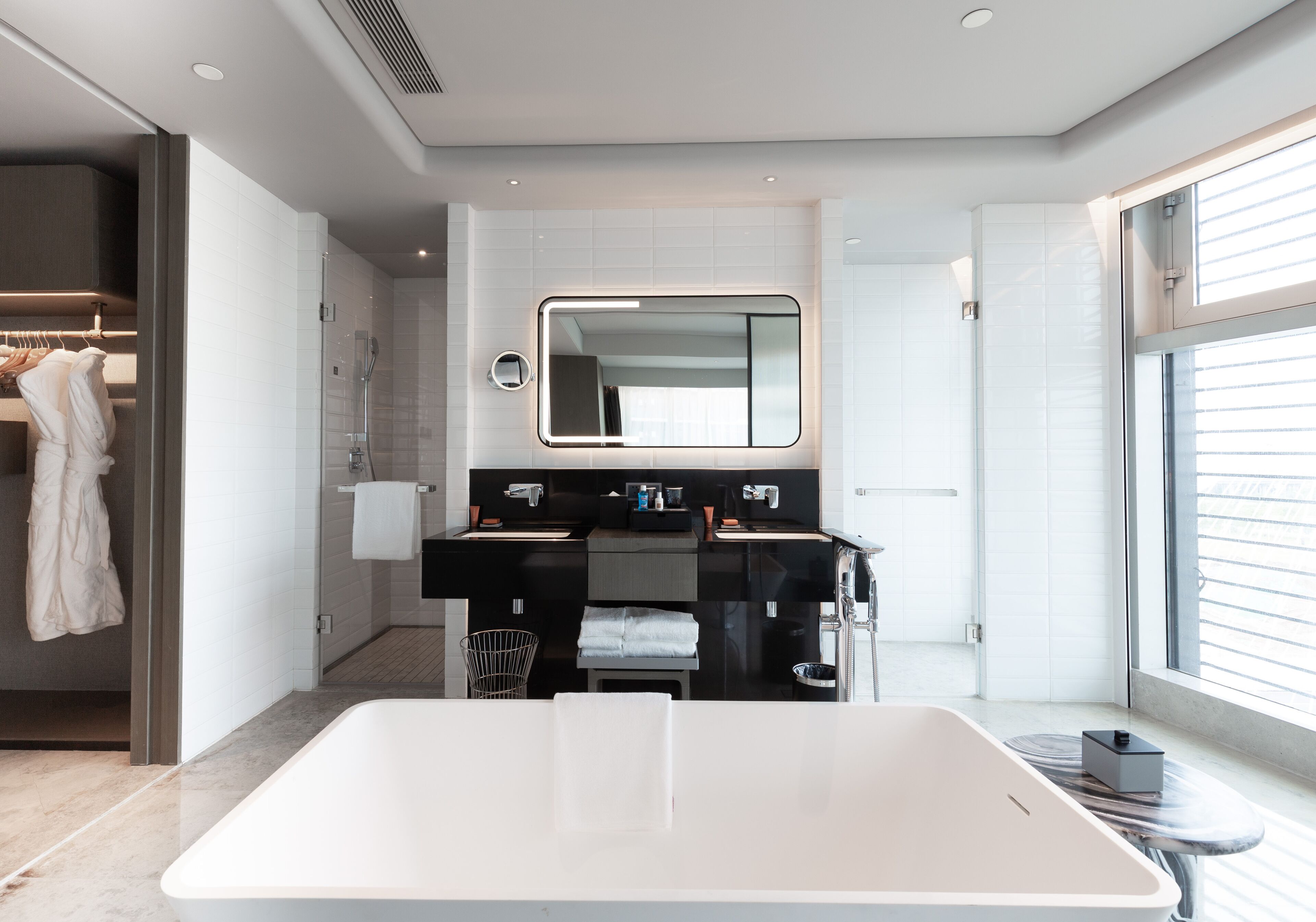 A modern bathroom with a large bathtub, a double sink vanity, a mirror, and a walk-in shower.