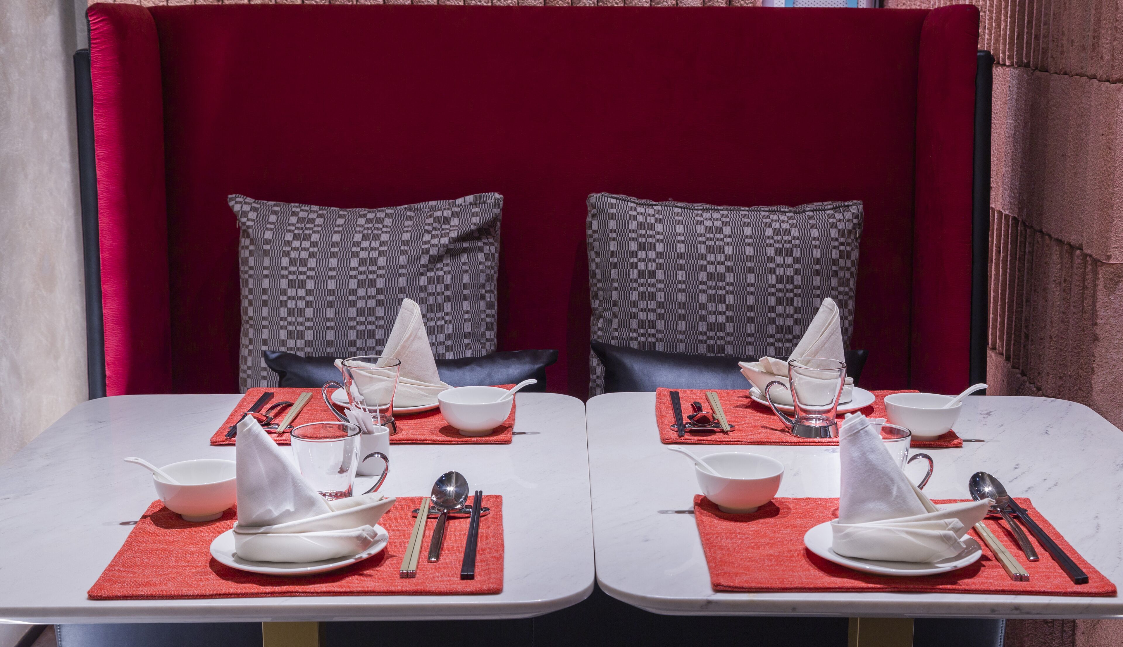 Two dining tables with red placemats, white bowls, and chopsticks.