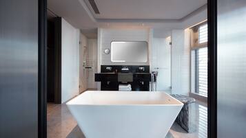 A modern bathroom with a large white bathtub, a black vanity with a mirror, and a window providing natural light.
