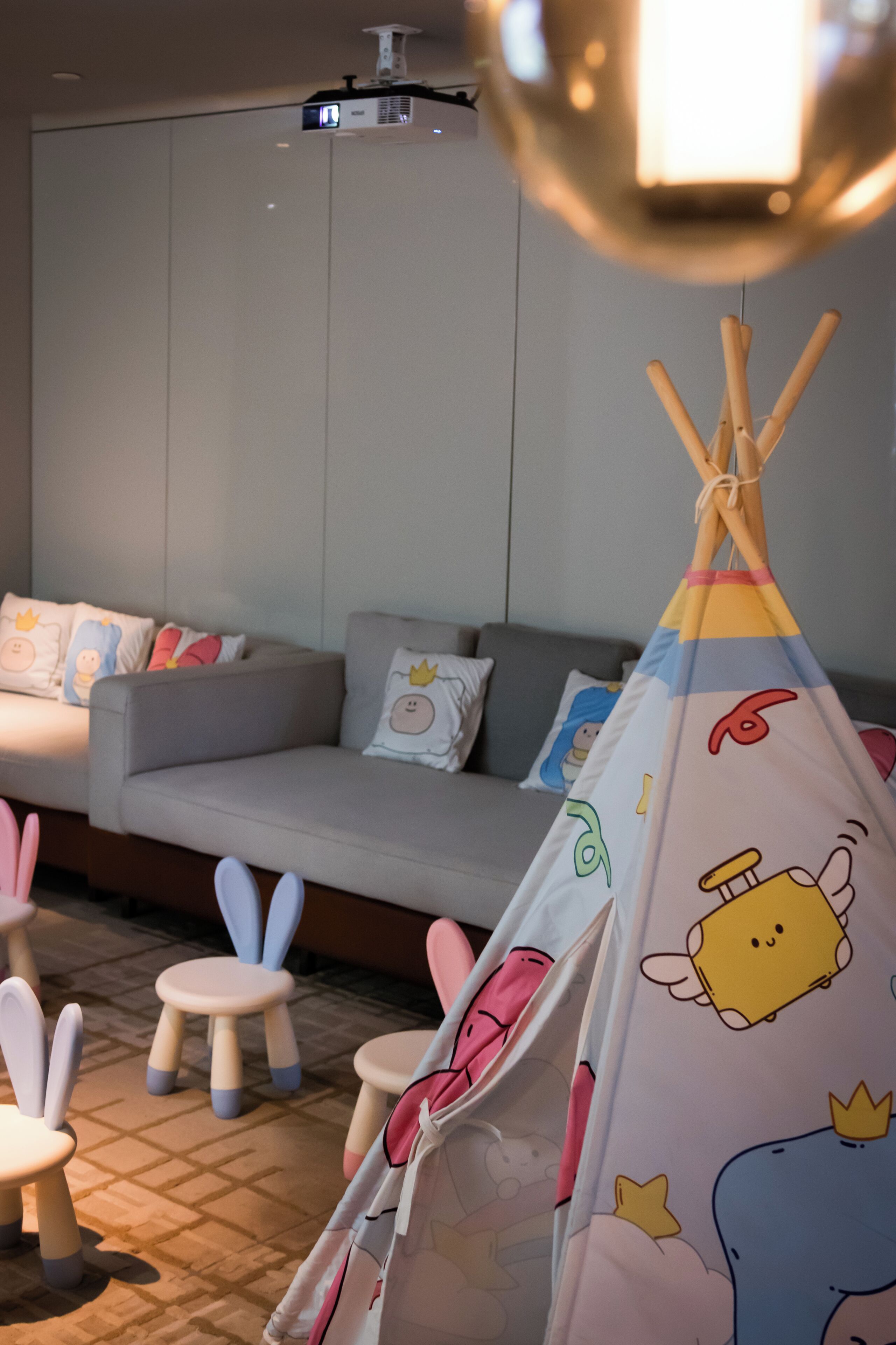Un espace de vie chaleureux avec un canapé, des coussins et une tente de jeu colorée pour enfants.