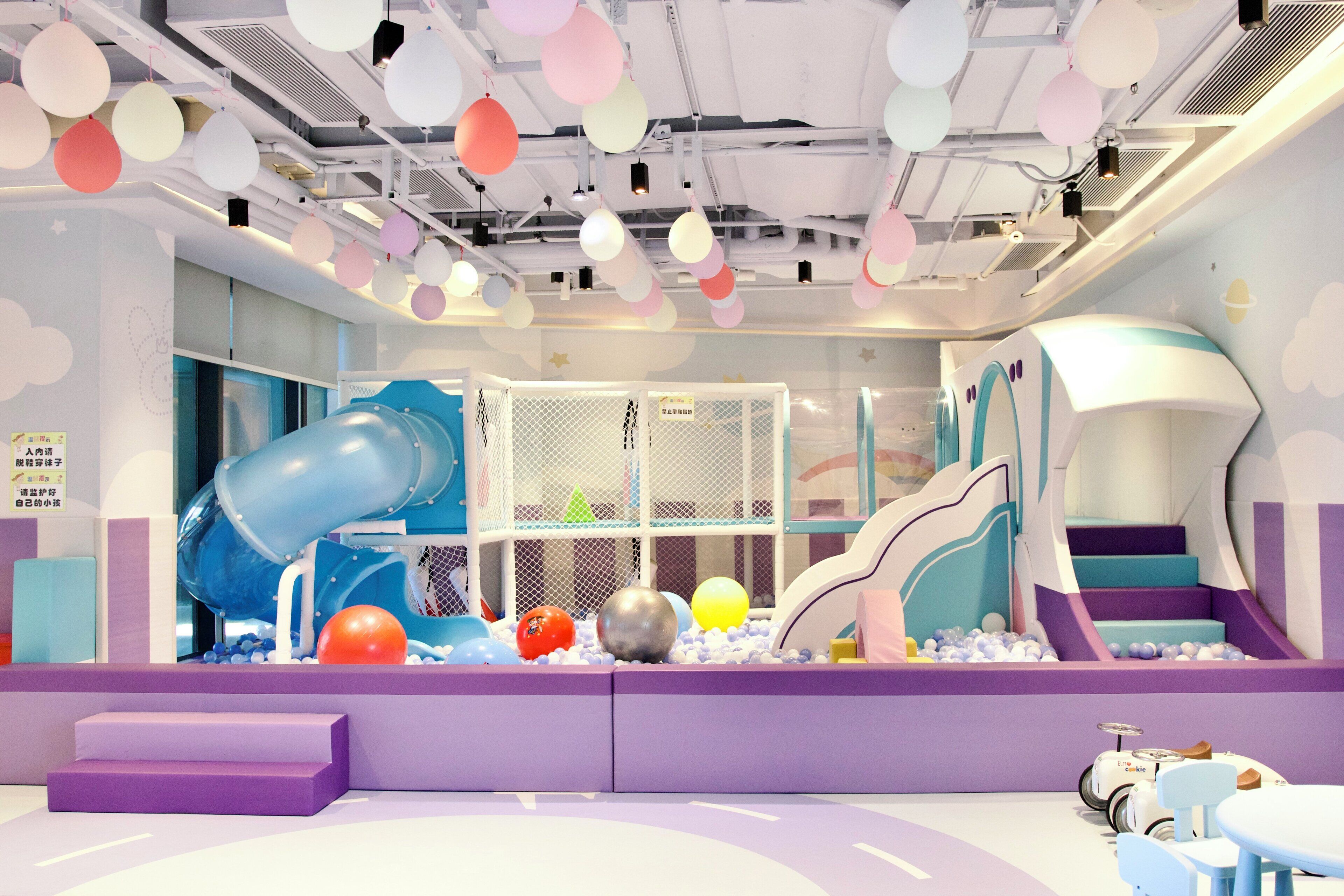 A children's play area with a slide, climbing net, and ball pit.
