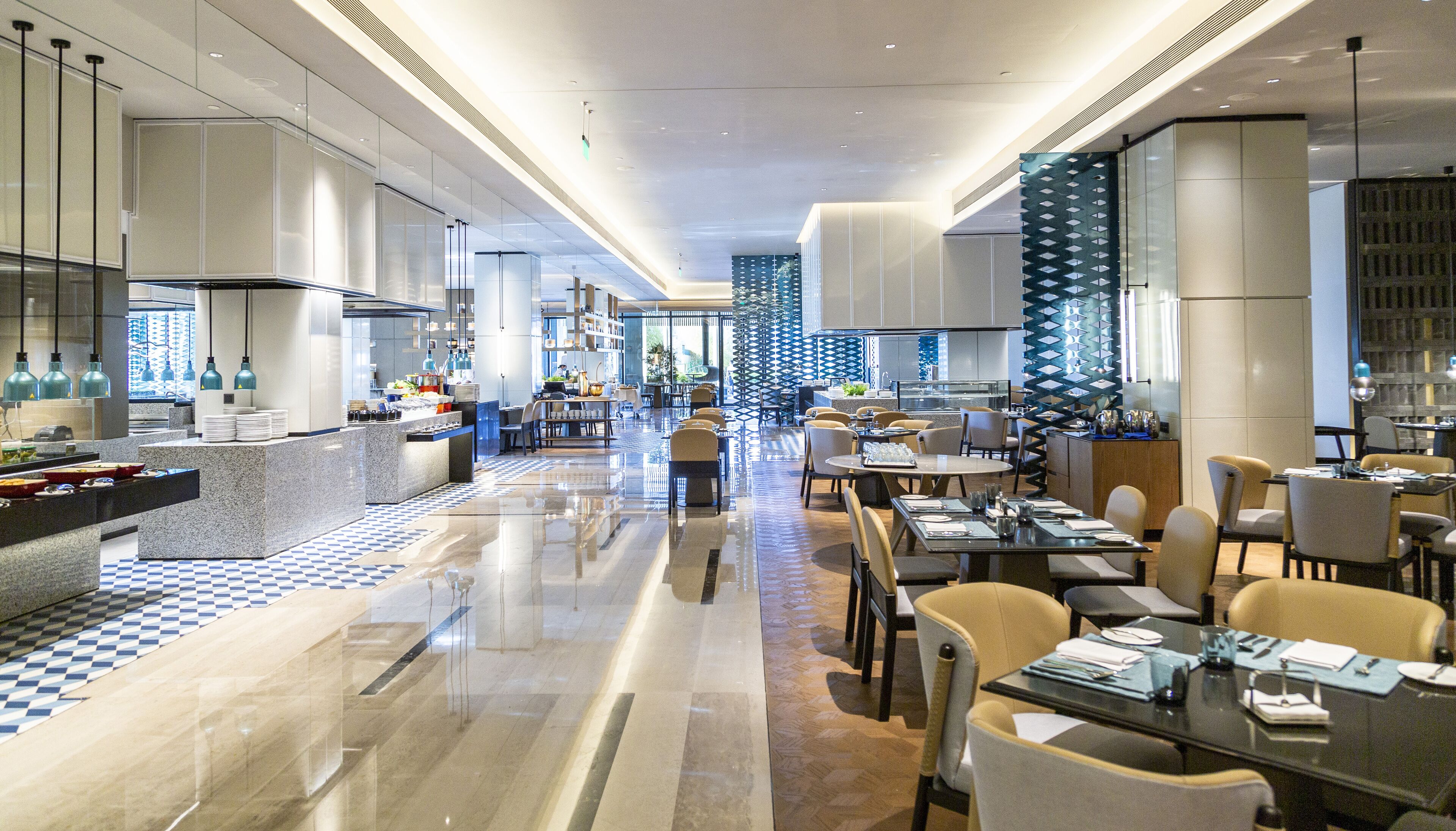 A modern hotel lobby with a checkered floor, a central bar area, and seating arrangements.