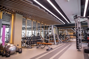 Ett gym med olika typer av träningsutrustning, inklusive hantlar, kettlebells och styrketräningsmaskiner.