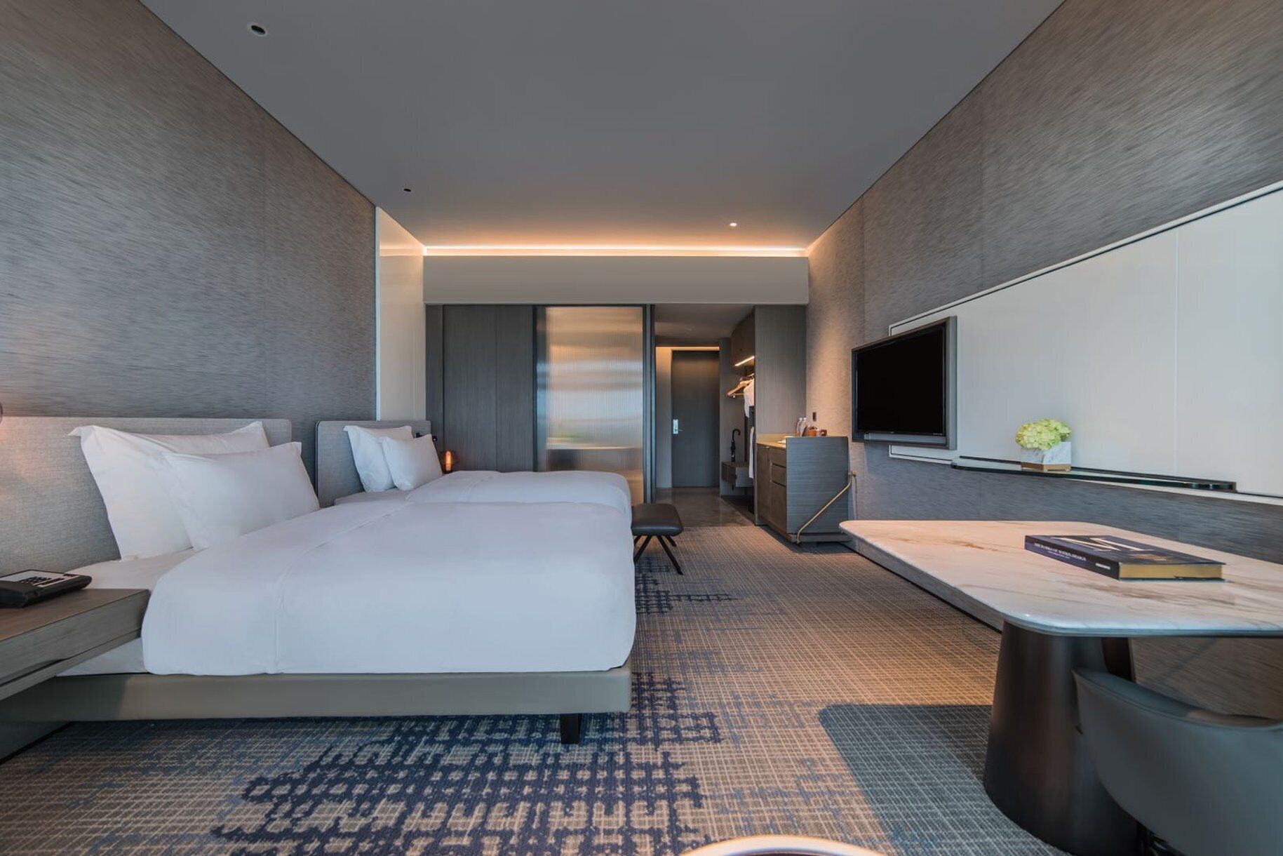 Quarto de hotel moderno com uma cama grande, uma escrivaninha, uma TV de tela plana e um closet espaçoso.