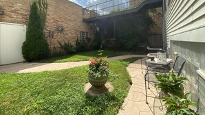 A brick building with a covered patio area, outdoor seating, and a small garden.