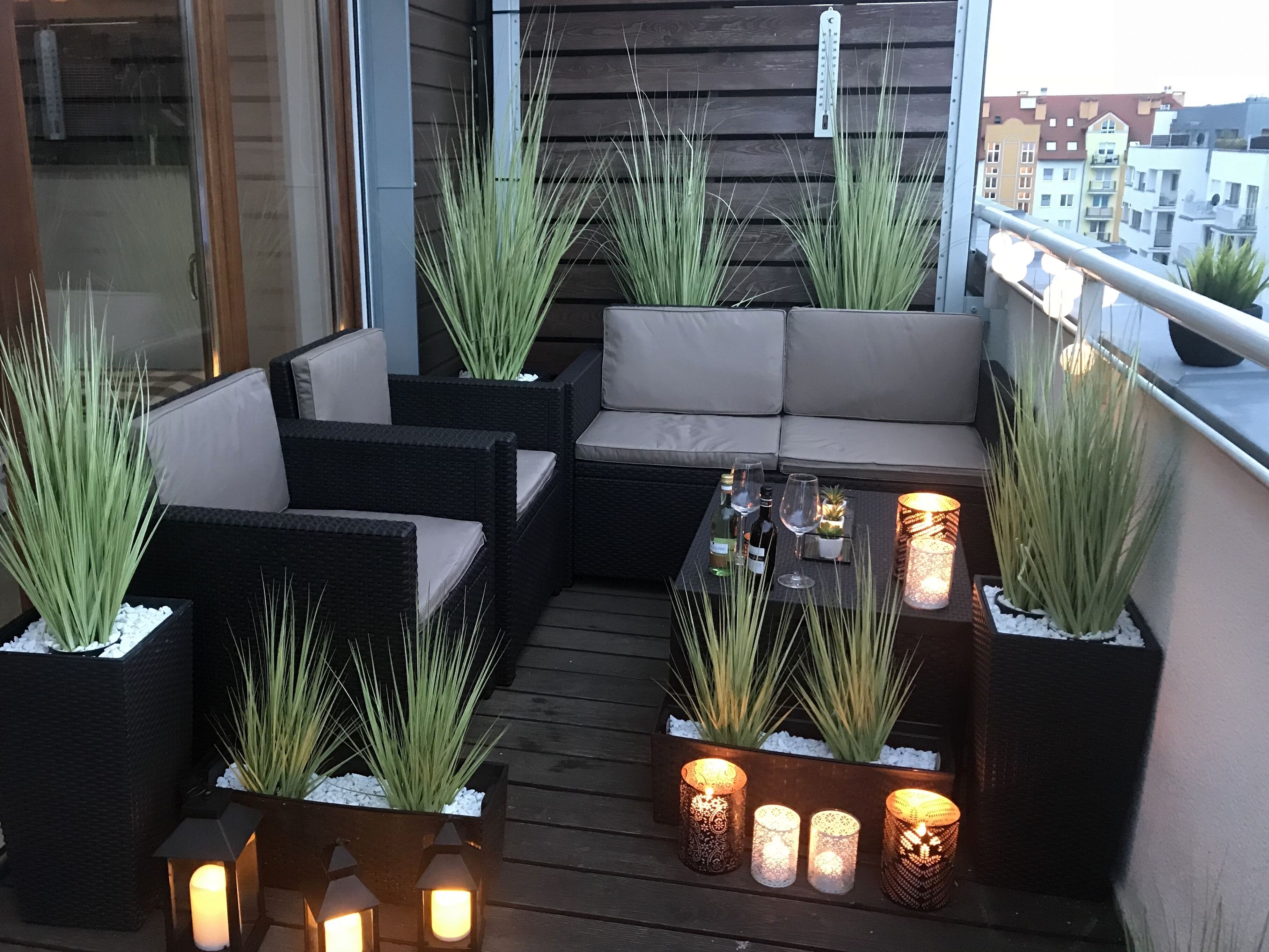 En balkon med fletmøbler, blomsterkrukker og stearinlys.