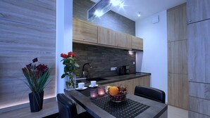 Une cuisine moderne avec des meubles en bois, un plan de travail noir et un coin repas comprenant une table et des chaises.