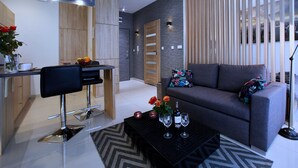 Un salon moderne avec un canapé, une table basse et un coin repas comprenant une chaise et un saladier rempli de fruits.