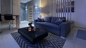 Un salon moderne avec un canapé gris, une table basse noire et un tapis à motifs.