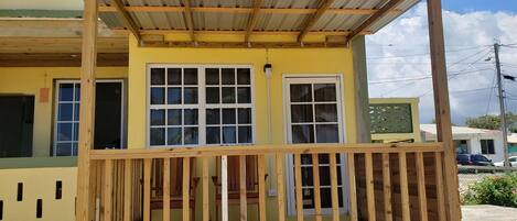 A yellow building with a wooden porch and multiple windows.