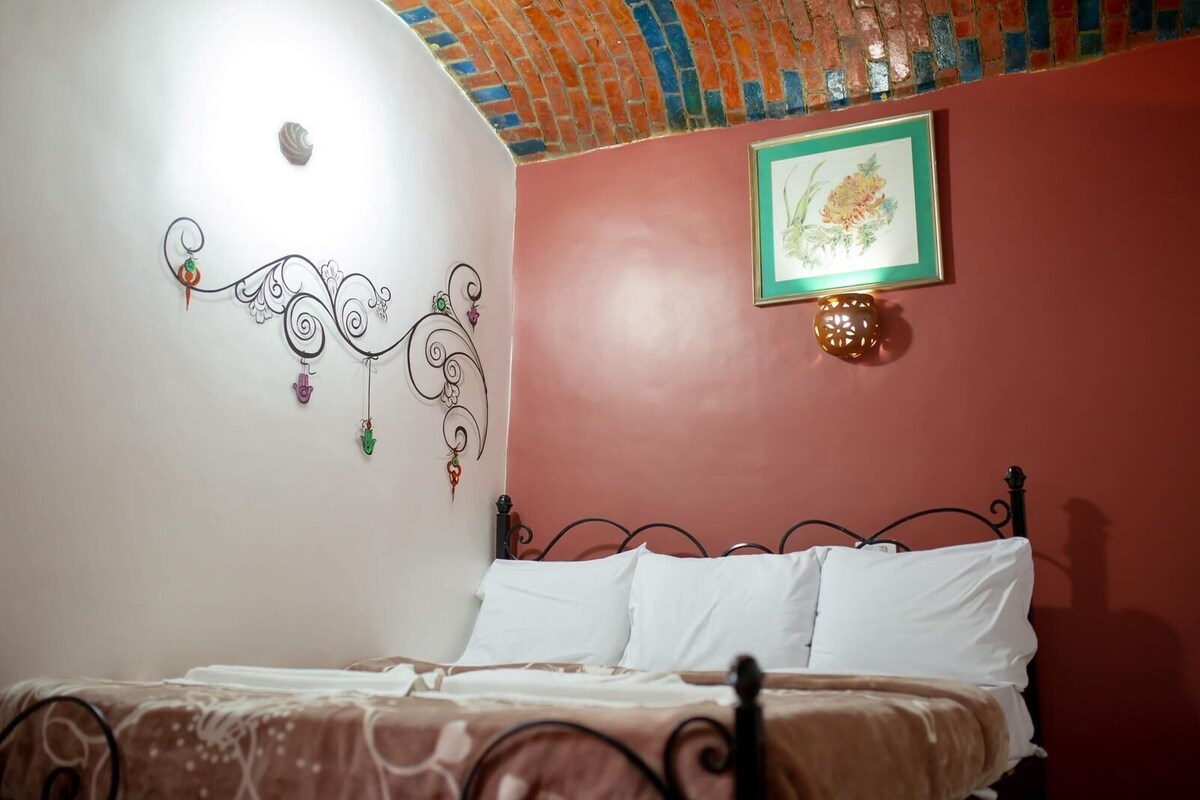 A bedroom with a bed, a decorative wall piece, and a framed picture.