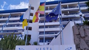 A building with the sign "VISTA TAURITO" and multiple flags including the Spanish and EU flags. - Amazing ocean view apartment in Taurito, Mogán (Mogan)