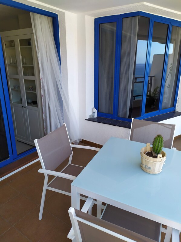 A balcony with a white table, chairs, and a potted cactus. - Amazing ocean view apartment in Taurito, Mogán (Mogan)