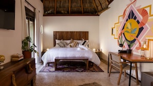 Un dormitorio con cama, mesita de noche, lámpara, silla y un adorno en la pared.