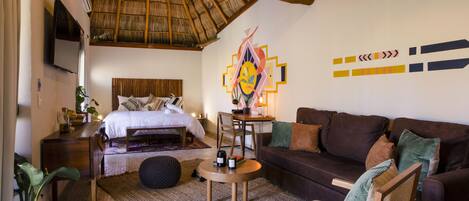 A bedroom with a bed, a sofa, a coffee table, and a TV.