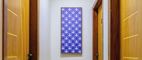 Un pasillo con puertas de madera numeradas 10 y 08, suelo de baldosas y un adorno mural azul con estampado.