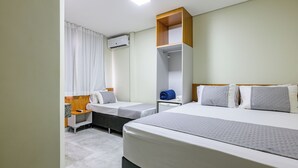 A hotel room with two beds, a wardrobe, a bedside table, an air conditioning unit, and a window with curtains. - OYO Hotel Brisa Tropical, Brasília (São Sebastião)