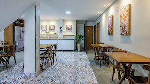 A modern dining area with wooden tables and chairs, a patterned floor, and artwork on the walls. - OYO Hotel Brisa Tropical, Brasília (São Sebastião)