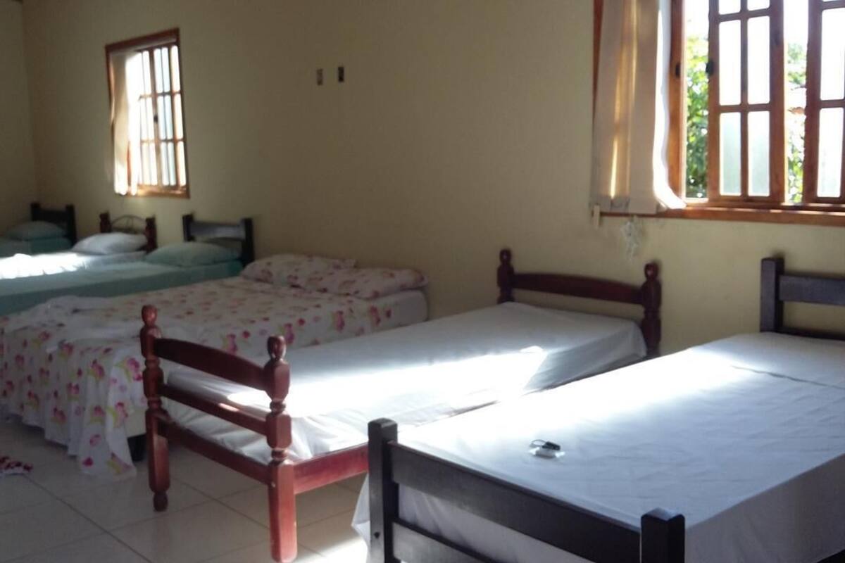 A room with two single beds, a wooden headboard, a small rug, and a window with curtains.