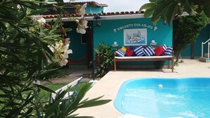 A pool area with a bench and a mural reading "ENCANTO DOS ANJOS". - OYO Pousada Encanto dos Anjos (Búzios)