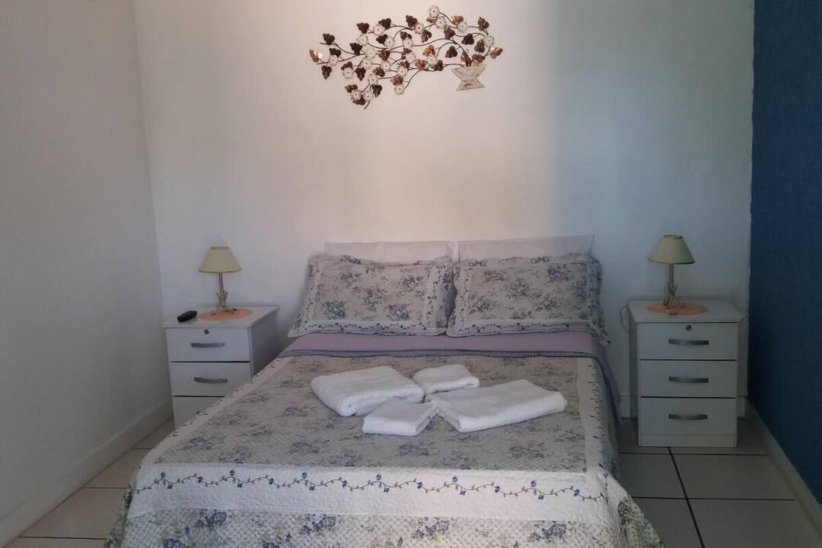 A bedroom with a bed, two nightstands, a decorative wall piece, and a blue accent wall.